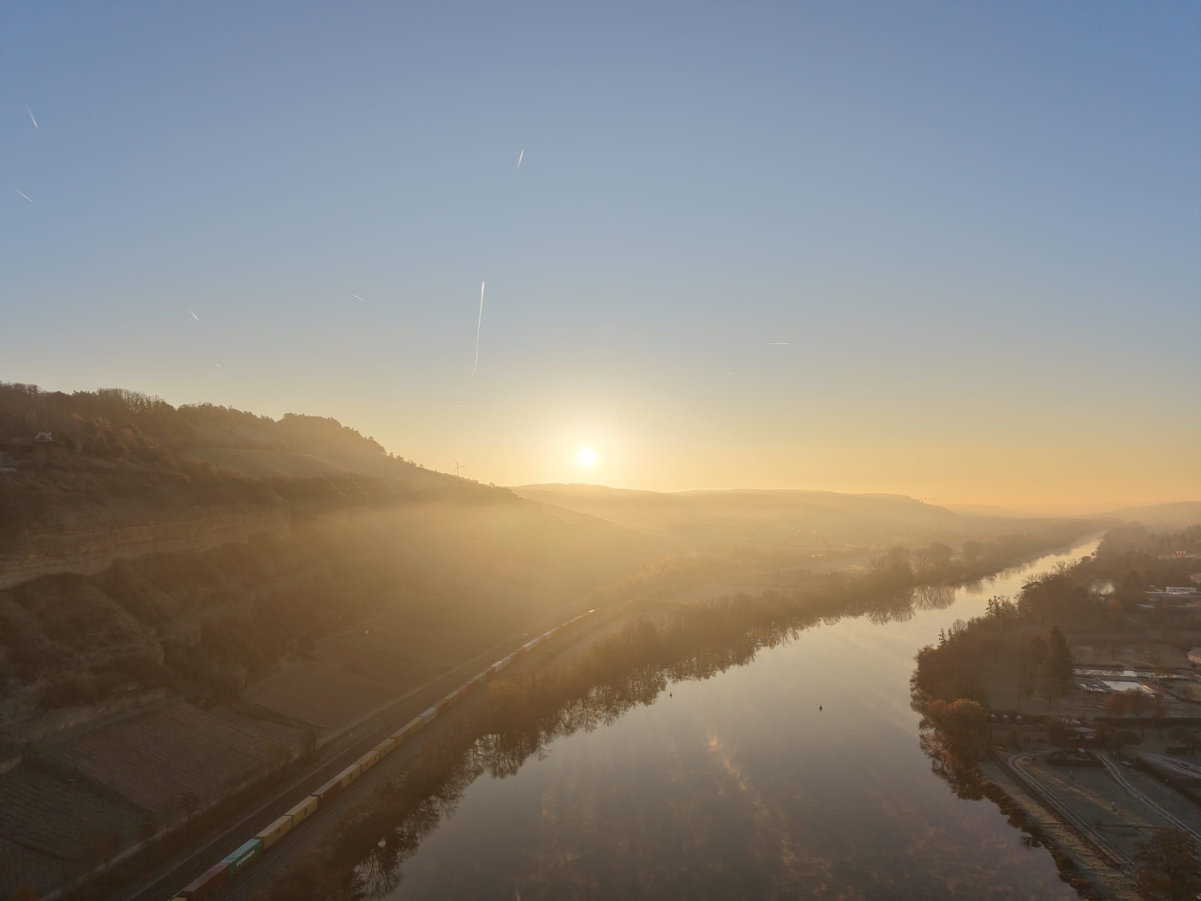 Das Maintal bei Sonnenaufgang mit Weinbergen und Nebel über dem Fluss